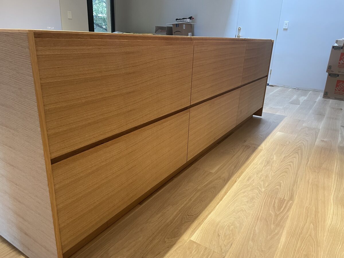 Integrated J-pull handle on white oak cabinet door