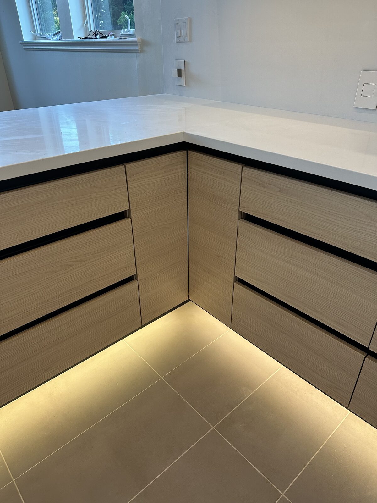 Toekick lighting and finger pull channels on white oak cabinets — DodiHome