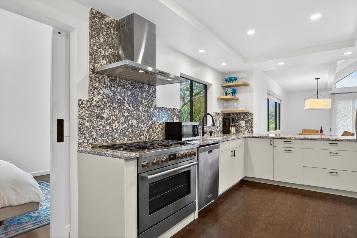 Painted flat panel kitchen with patterned stone backsplash and gas range — DodiHome Mill Valley