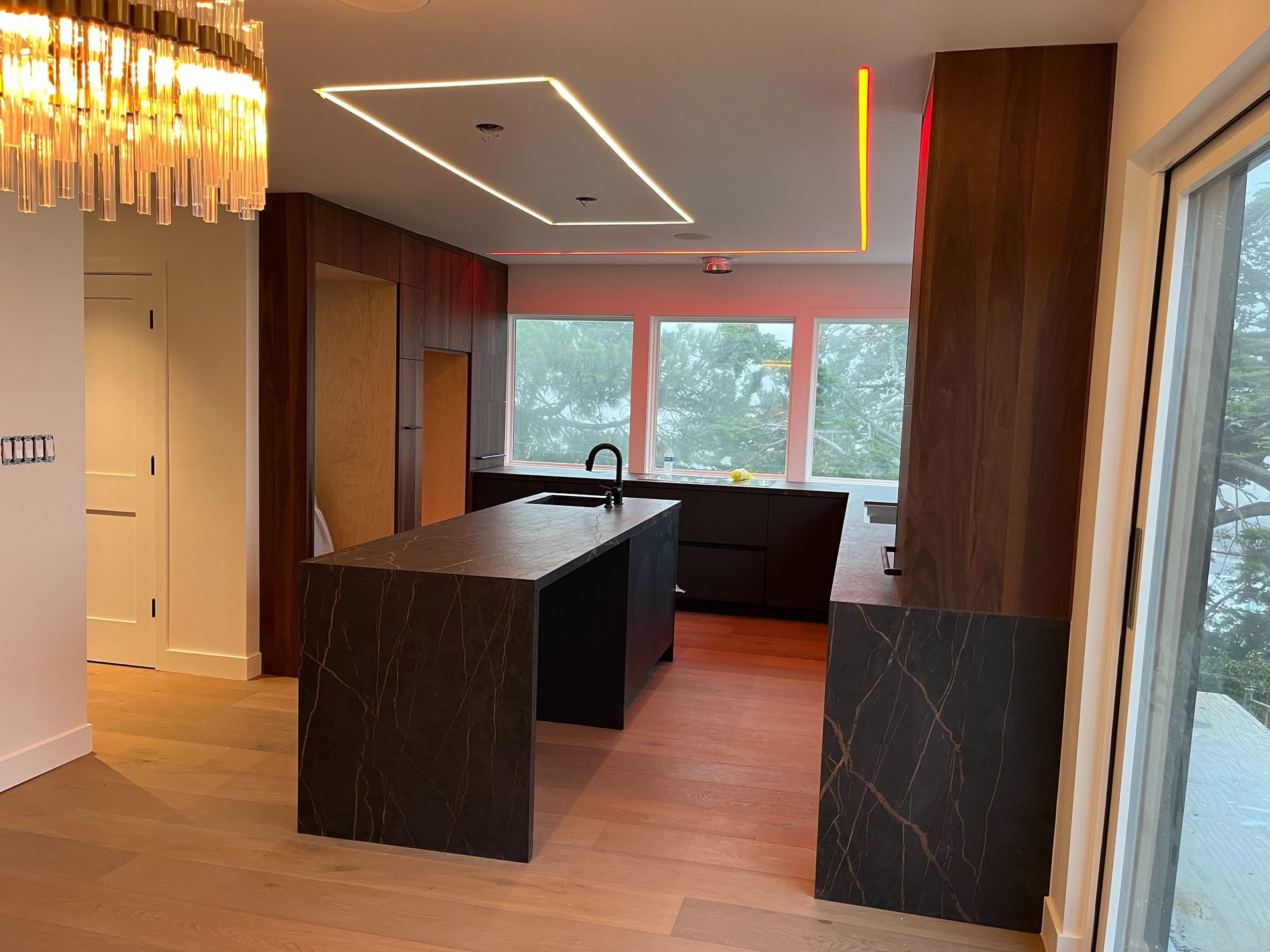 Primary finished-room view of black island & walnut kitchen cabinetry and surrounding surfaces