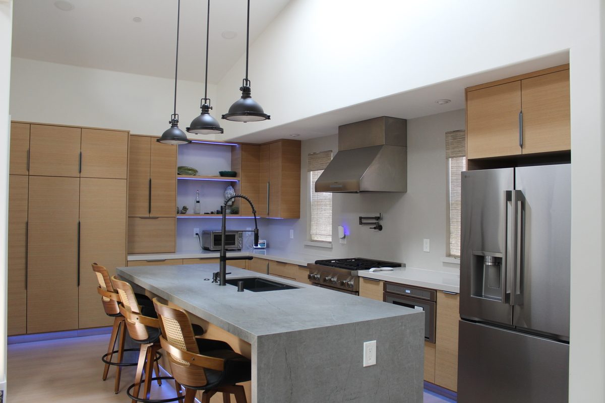 Pulled-back view of the rift oak kitchen showing the vaulted ceiling and full cabinet run beside the island