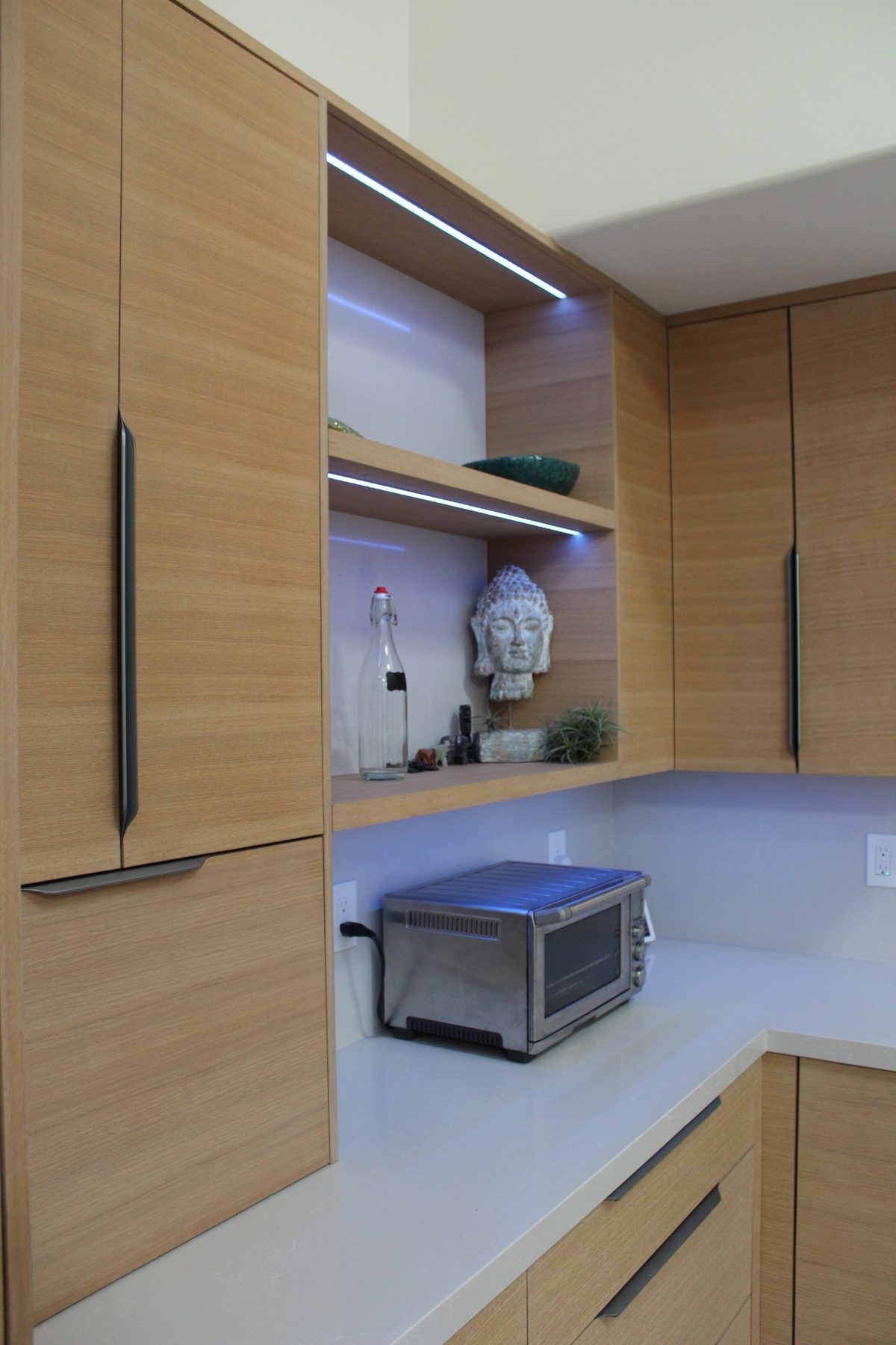 Styled open kitchen shelving with integrated LED strip lighting above built-in oak cabinetry