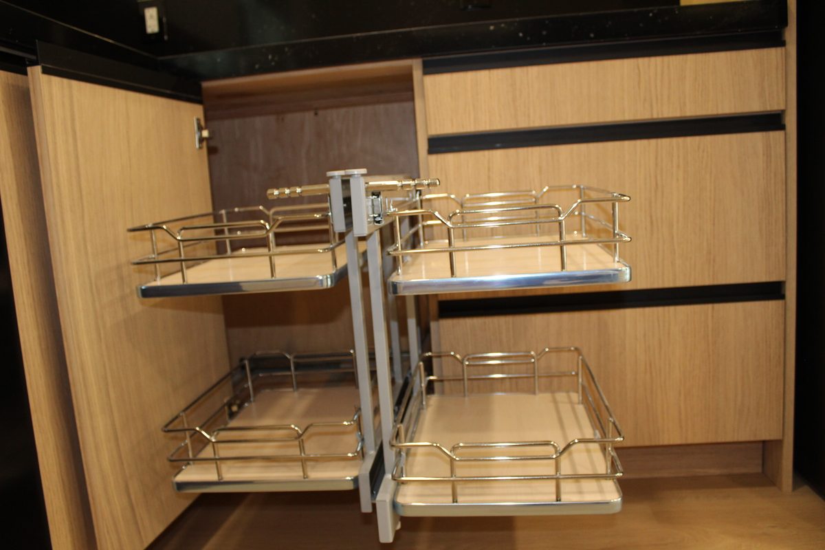 Pull-out wire basket storage extended from a light oak base cabinet in the kitchen