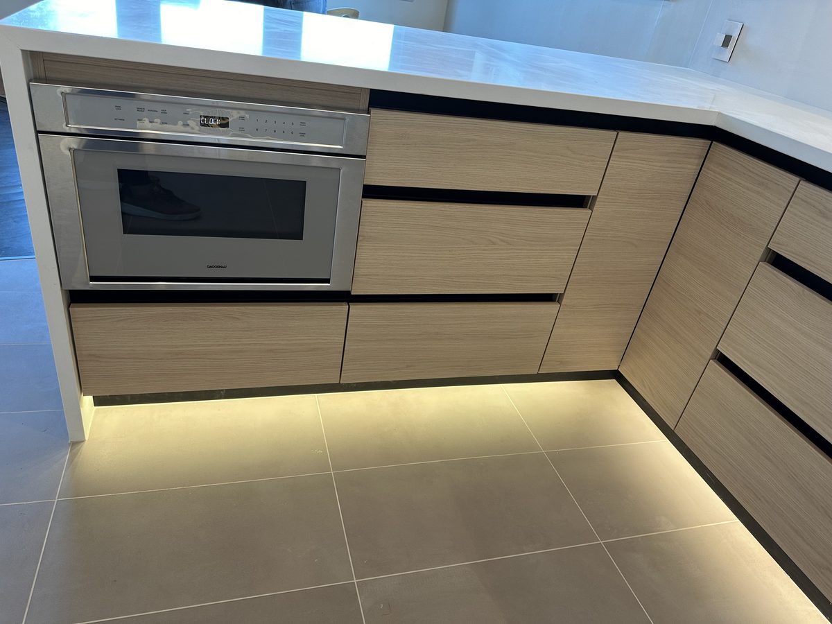 Second finished-room view of light oak kitchen with integrated lighting cabinetry and surrounding surfaces