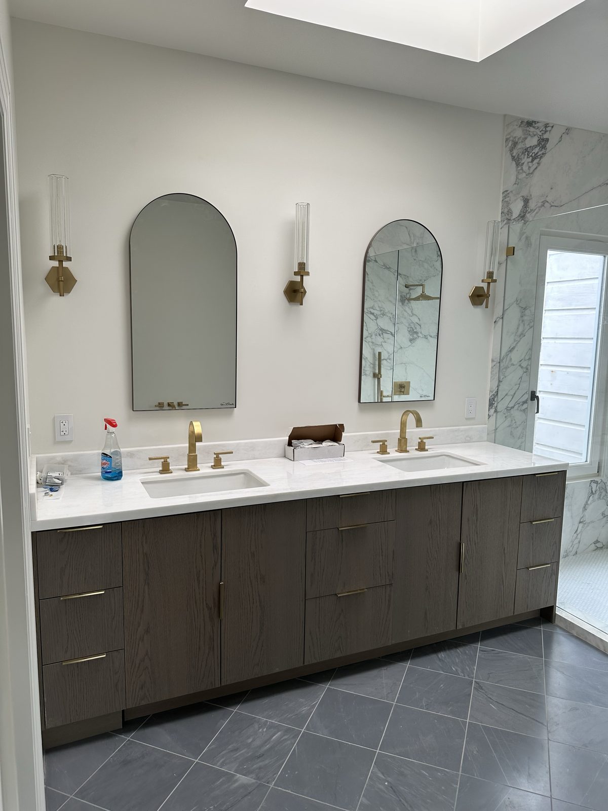 Dark wood vanity detail with brass fixtures and marble surround in the primary bathroom